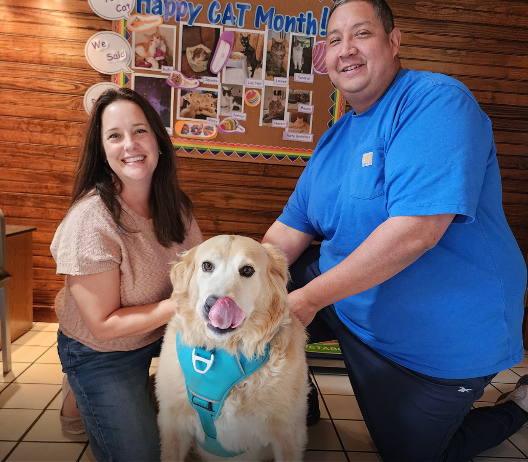 Dr. Bachman and Dr. Jim posing with overweight golden retriever licking her lips.